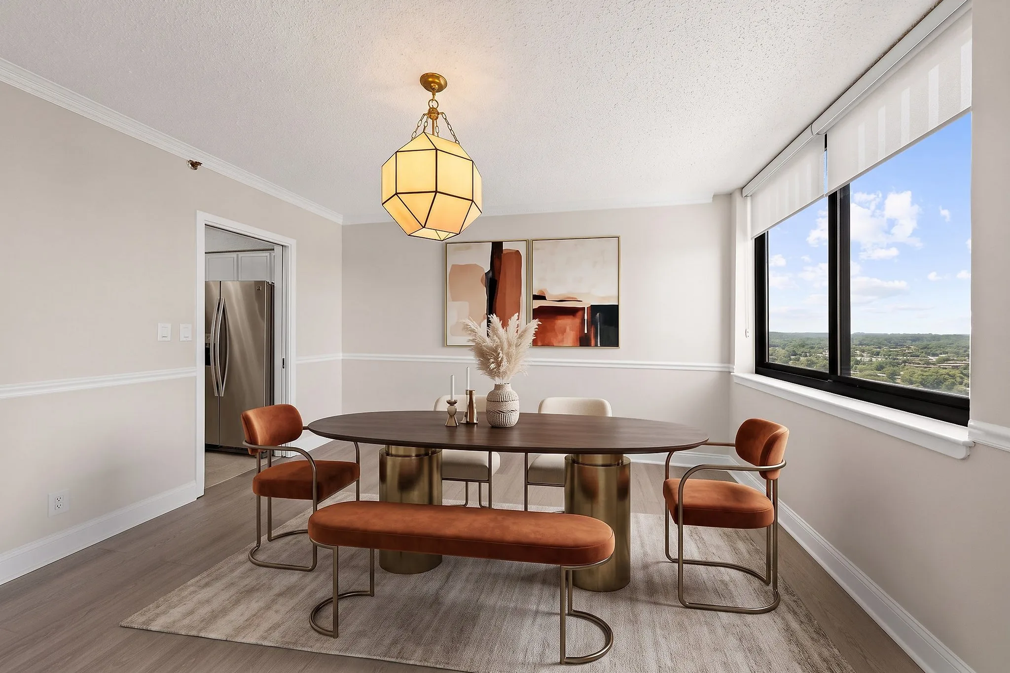 The same dining room virtually staged with an oval wood table on brass pedestals, rust velvet chairs and bench, a rug and abstract wall art