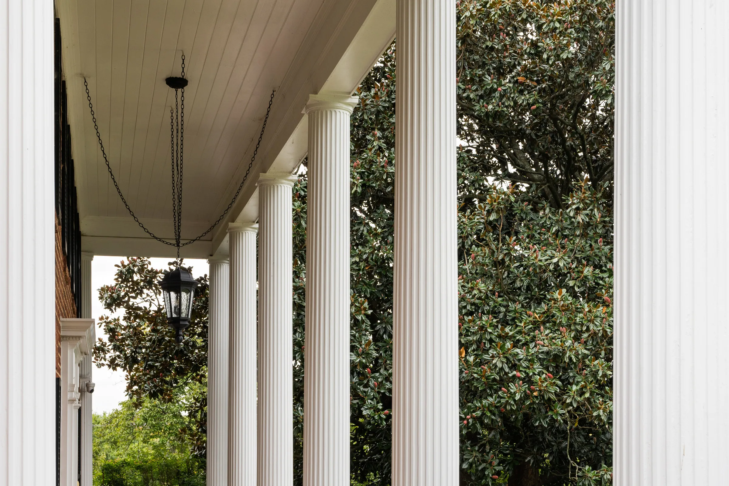 Before: a front porch with fluted white columns and a hanging lantern in soft, grey daylight